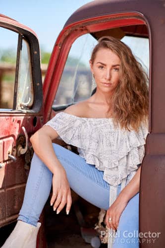 Sitting and looking out the door of her old truck.