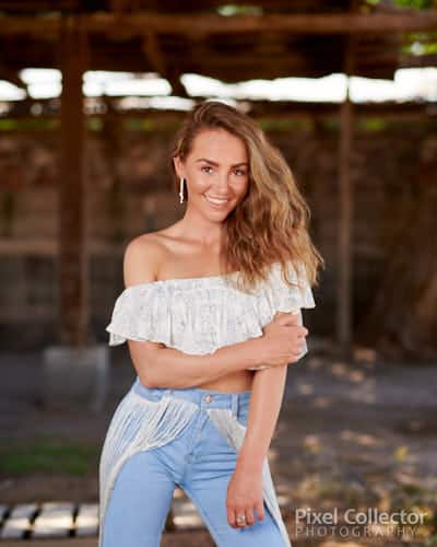 Cute country girl smiling and looking at the camera while in a barn.