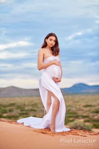 A woman standing and holding her belly during her maternity session.